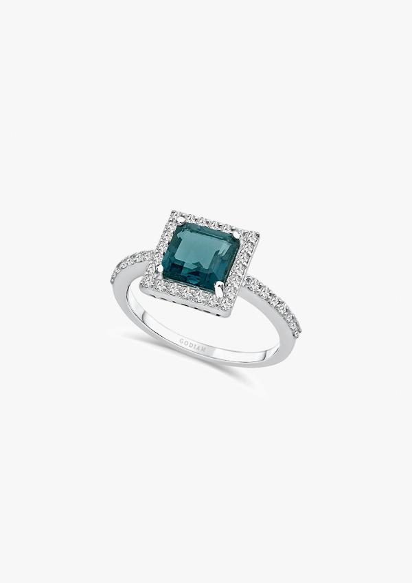 LUCÍA 18K white gold ring with a halo of brilliant cut diamonds topped by a princess cut London Blue topaz